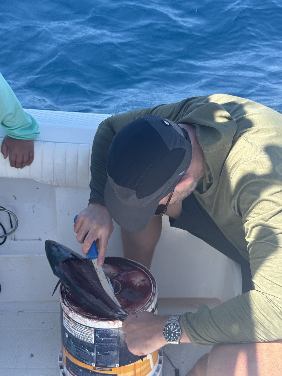 Bleeding the caught fish on a bucket on the boat deck.